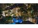Luxury estate featuring resort-style backyard with pool, spa, mature palms, and lush landscaping illuminated at night at 2818 E Quail Ave, Las Vegas, NV 89120