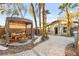 Outdoor space with a gazebo, conversation set with fire pit, and lush palm trees creating a private retreat at 2818 E Quail Ave, Las Vegas, NV 89120