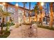 Outdoor seating area with a table, chairs, lush tropical landscaping, and exterior string lights at 2818 E Quail Ave, Las Vegas, NV 89120