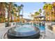 Circular, mosaic-tiled hot tub with integrated spillway, sitting adjacent to a lush, tropical pool area and cabana at 2818 E Quail Ave, Las Vegas, NV 89120