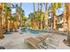 Resort-style backyard featuring long pool with fountains, lounge chairs and abundant palm trees offering shade at 2818 E Quail Ave, Las Vegas, NV 89120