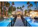 Luxurious backyard with a bridge over a pool to a cabana and palm trees at 2818 E Quail Ave, Las Vegas, NV 89120