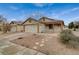 Beige home with desert landscaping, a two-car garage, and covered front porch at 612 Bullwhip Ct, Henderson, NV 89011