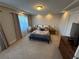 Bedroom features neutral walls and carpet, a queen bed, side tables, and natural light through curtains at 7068 Parrot Bay Way, Las Vegas, NV 89118