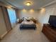 Bedroom features neutral walls and carpet, a queen bed, side tables, and natural light through curtains at 7068 Parrot Bay Way, Las Vegas, NV 89118