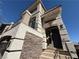 A close-up of the home's front entrance with stone accents, modern lighting, and a private balcony at 7068 Parrot Bay Way, Las Vegas, NV 89118