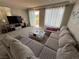 Bright living room with a large sectional sofa, neutral carpet, and natural light at 7068 Parrot Bay Way, Las Vegas, NV 89118