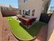 Cozy patio area with artificial turf, red rock features, and comfortable outdoor seating with access gate at 7068 Parrot Bay Way, Las Vegas, NV 89118