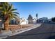 Single-story home with a xeriscape front yard, featuring mature palm trees, and a two-car garage at 8072 Big Top Dr, Las Vegas, NV 89123