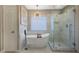 This bright bathroom features a large soaking tub and glass-enclosed shower with white tile at 9601 Rolling Thunder Ave, Las Vegas, NV 89148