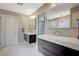 The bright bathroom has dual sinks with dark wood cabinetry and tile floors at 9601 Rolling Thunder Ave, Las Vegas, NV 89148