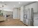 Modern kitchen with stainless steel refrigerator, white cabinetry, and an open layout to the living room at 9601 Rolling Thunder Ave, Las Vegas, NV 89148