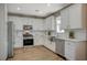 Modern kitchen with stainless steel appliances, white cabinetry, granite countertops, and wood-look flooring at 9601 Rolling Thunder Ave, Las Vegas, NV 89148
