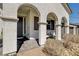 Covered front porch with decorative pillars, dark front door, and outdoor seating area at 10064 Ocher Valley Ave, Las Vegas, NV 89178
