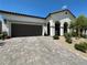 Inviting home featuring a two-car garage, paver driveway, arched entrance, and desert landscaping at 10064 Ocher Valley Ave, Las Vegas, NV 89178