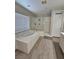 Bathroom with a large tub, glass enclosed shower, and wood-look floors at 10215 Radcliffe Peak Ave, Las Vegas, NV 89166