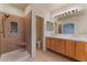Primary bathroom with a glass shower, double sinks, and wooden drawers for storage at 1405 San Juan Hills Dr # 104, Las Vegas, NV 89134
