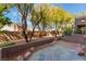 Beautiful outdoor patio area with stone tiles, desert landscaping, mature trees, and a privacy wall at 1405 San Juan Hills Dr # 104, Las Vegas, NV 89134