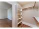 Well-organized walk-in closet with built-in shelving and wooden clothes racks for ample storage in neutral colors at 1405 San Juan Hills Dr # 104, Las Vegas, NV 89134