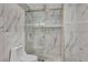Modern bathroom shower with marble tiles, gold trim, glass door, and geometric tile accents at 174 Buena Ct, Henderson, NV 89074