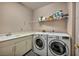 Functional laundry room with modern washer and dryer, sink, and storage cabinets at 174 Buena Ct, Henderson, NV 89074