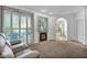 A cozy sitting area by a fireplace with neutral walls and carpet flooring, a large sliding glass door, and white shutters at 174 Buena Ct, Henderson, NV 89074