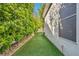 Narrow side yard featuring low-maintenance artificial turf, a privacy hedge, and a stone border at 174 Buena Ct, Henderson, NV 89074