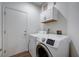 The laundry room has new machines and cabinets for storage with adjacent entry door at 2517 New Salem Ave, Henderson, NV 89052