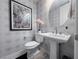 Stylish powder room featuring patterned wallpaper, pedestal sink, and a modern round mirror at 343 Cadence Vista Dr, Henderson, NV 89011