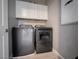 Modern laundry room with a full-size washer and dryer, plus overhead white storage cabinets at 343 Cadence Vista Dr, Henderson, NV 89011