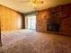 Spacious carpeted living room featuring a brick fireplace and wood paneling at 4964 Dunkirk Ave, Las Vegas, NV 89121