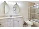 Bright bathroom featuring a double vanity, oval mirrors, and a glass-enclosed shower over tub at 5092 Mandalay Springs Dr # 201, Las Vegas, NV 89120