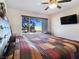Bedroom featuring a large window with backyard views, complemented by a ceiling fan and mounted TV at 5092 Mandalay Springs Dr # 201, Las Vegas, NV 89120