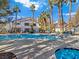 Community pool surrounded by tall palm trees and lounge chairs on a sunny day at 5092 Mandalay Springs Dr # 201, Las Vegas, NV 89120