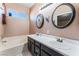 Bathroom featuring double sink vanity, tub and shower, and round mirrors at 6224 Mandarin Dr, Las Vegas, NV 89108