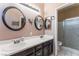 Bathroom featuring double sinks with round mirrors, and a glass-enclosed shower at 6224 Mandarin Dr, Las Vegas, NV 89108