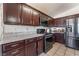 A well-equipped kitchen featuring stainless appliances, granite countertops, dark wood cabinets, and tiled floors at 6224 Mandarin Dr, Las Vegas, NV 89108