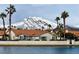 Single-story home with a red tile roof near a lake with a view of snow-capped mountains at 7624 Nocturne Ct, Las Vegas, NV 89128