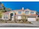 Traditional two-story home with tile roof, lush desert landscaping, and an attached two-car garage at 7624 Nocturne Ct, Las Vegas, NV 89128