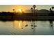 Scenic lake view at sunset, featuring ducks swimming in the water and palm trees silhouetted against the colorful sky at 7624 Nocturne Ct, Las Vegas, NV 89128