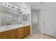 A well-lit bathroom with double sinks, tile floors and a view to the hall at 10808 Aire Dr, Las Vegas, NV 89144