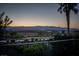 Expansive backyard view showcasing desert landscape, paved path, and picturesque mountains at dusk at 1219 Diamond Valley St, Henderson, NV 89052