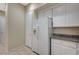 Well-lit kitchen featuring white cabinets, granite counters, tile floors, and modern refrigerator at 20 Serene Ave # 201, Las Vegas, NV 89123