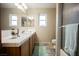 Well-lit bathroom with double sinks, tile countertops, and a shower with glass door at 2823 Landau Ct, Henderson, NV 89074