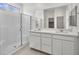 A bright bathroom features double sink vanity, large mirror, tile floors, a glass enclosed shower, and bright window at 637 N Water St, Henderson, NV 89015