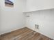 A functional laundry room with wood look floors, bright lighting, a shelf and hookups for a washer and dryer at 637 N Water St, Henderson, NV 89015
