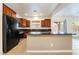 Bright kitchen with dark wood cabinets, black appliances, granite countertops, and tile flooring at 10858 La Florentina Ave, Las Vegas, NV 89166