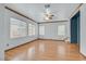 Open-concept living room with wood floors, multiple windows, ceiling fan, and staircase access at 10891 Colour Magic St, Henderson, NV 89052