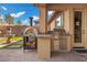 This outdoor kitchen features a built-in grill and pizza oven overlooking a water feature in the backyard at 2436 Chateau Napoleon Dr, Henderson, NV 89044