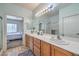 Bright bathroom featuring a double sink vanity with wood cabinets and large mirror at 3305 Fernbird Ln, North Las Vegas, NV 89084